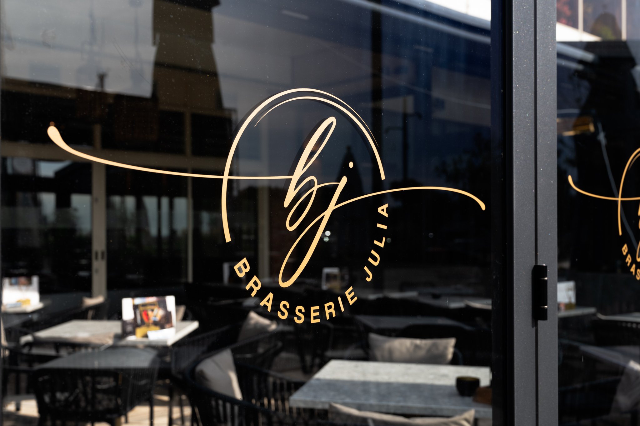 Glazen vouwwanden in terrasoverkapping voorzien van logo