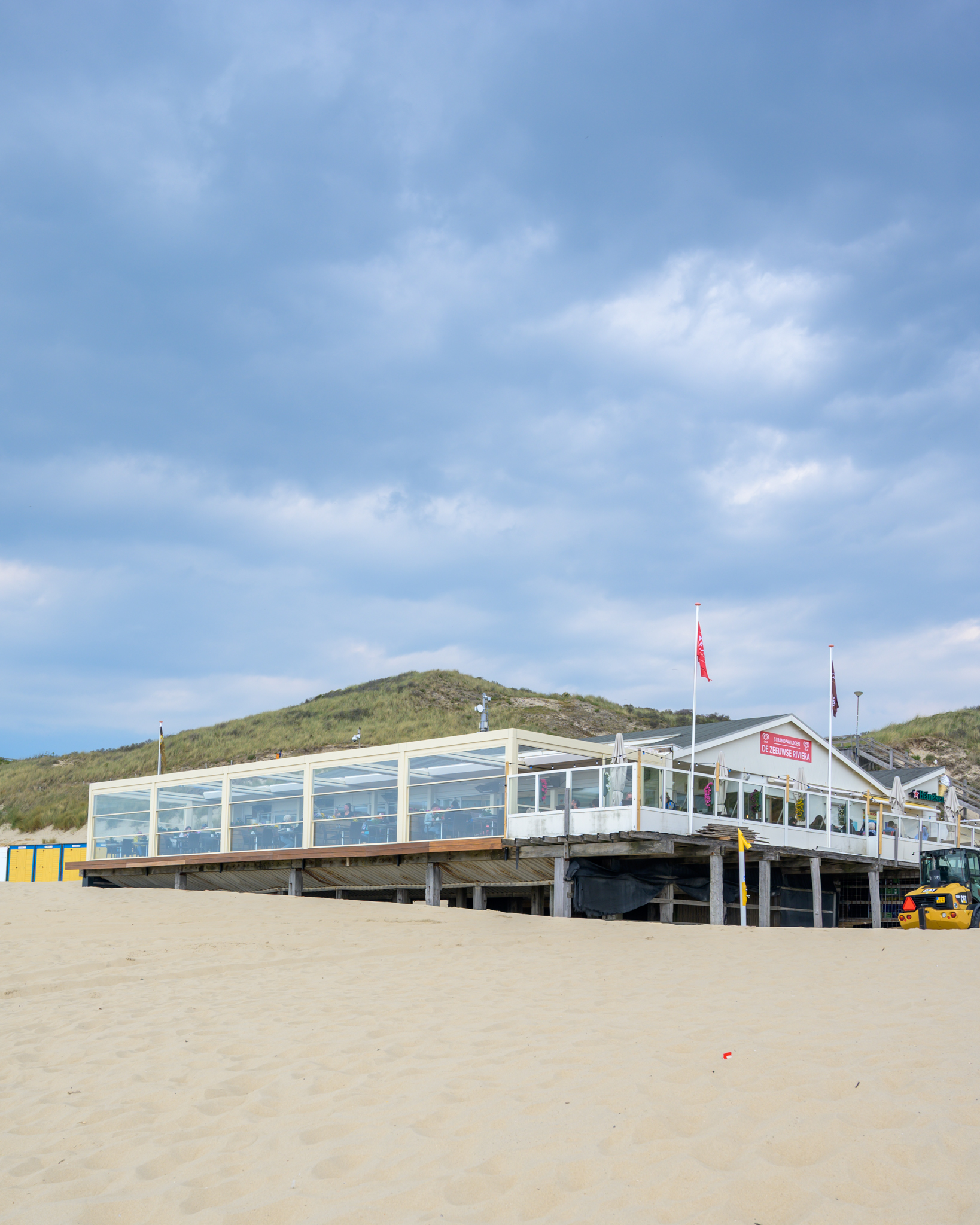 Jaarrond terras lamellen overkapping en glazen borstweringen op het strand